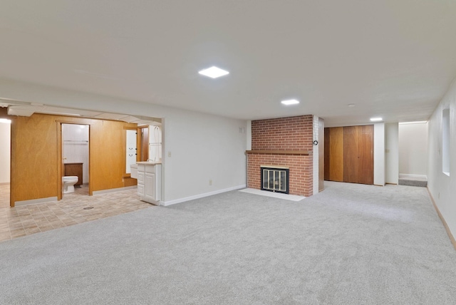 unfurnished living room featuring light carpet, a brick fireplace, and baseboards