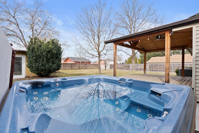 view of swimming pool with a deck, an outdoor hot tub, a fenced backyard, and a lawn