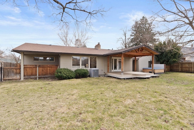 back of house with a yard, fence private yard, a chimney, and a hot tub