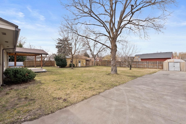 view of yard with a fenced backyard, a patio, an outdoor structure, and a shed