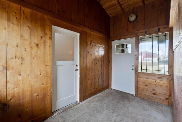 entryway featuring vaulted ceiling, carpet flooring, and wood walls