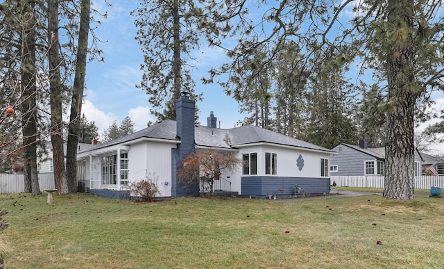 rear view of house featuring a yard, a chimney, and fence