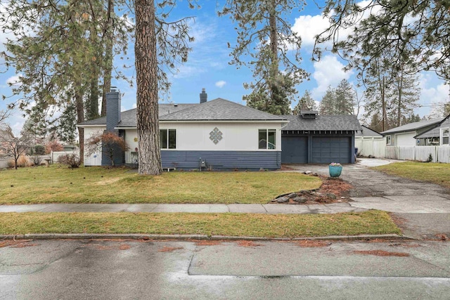 view of front of home with fence, roof with shingles, driveway, a chimney, and a front lawn