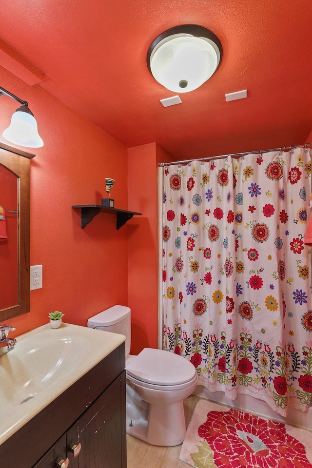 bathroom featuring curtained shower, toilet, and vanity