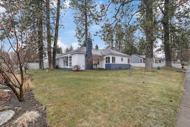 exterior space with a chimney, a front lawn, and fence