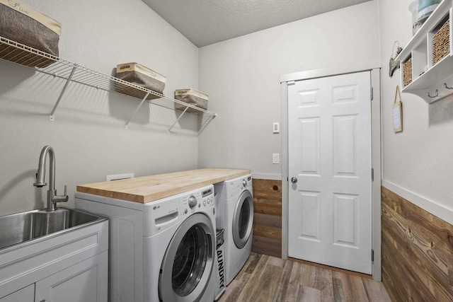 clothes washing area with dark wood-type flooring, washer and clothes dryer, a sink, a textured ceiling, and laundry area