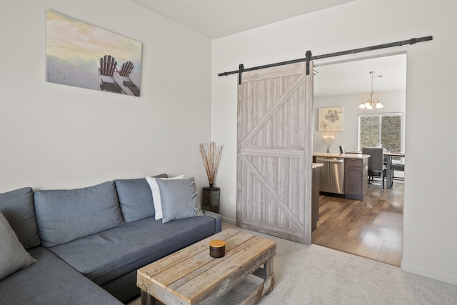 carpeted living area featuring an inviting chandelier, baseboards, a barn door, and wood finished floors