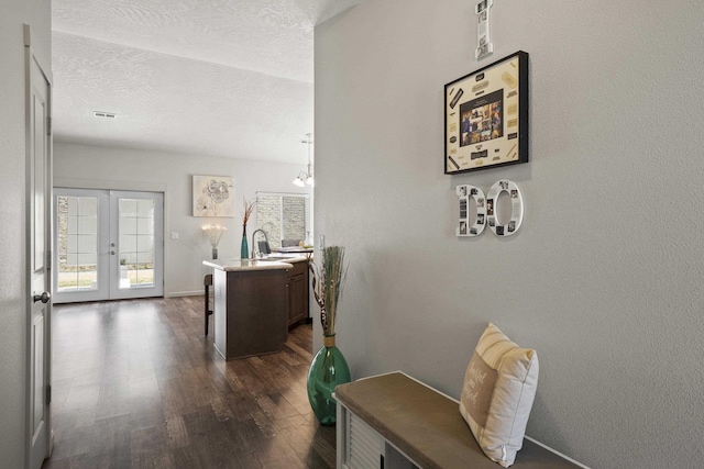 hallway featuring a sink, french doors, dark wood-style flooring, and a textured ceiling