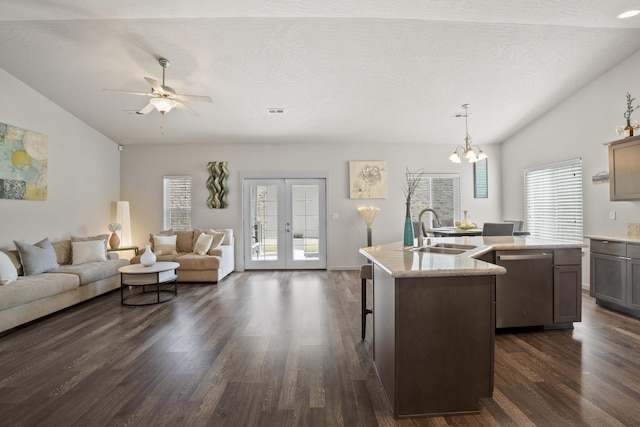 kitchen with a sink, open floor plan, dishwasher, vaulted ceiling, and a kitchen island with sink