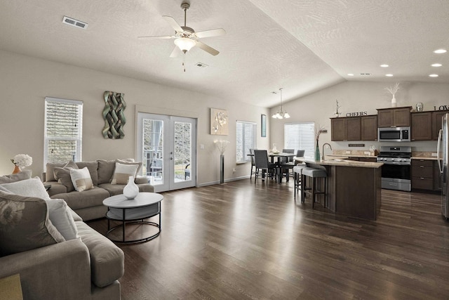 living room with visible vents, lofted ceiling, dark wood-style flooring, and ceiling fan with notable chandelier