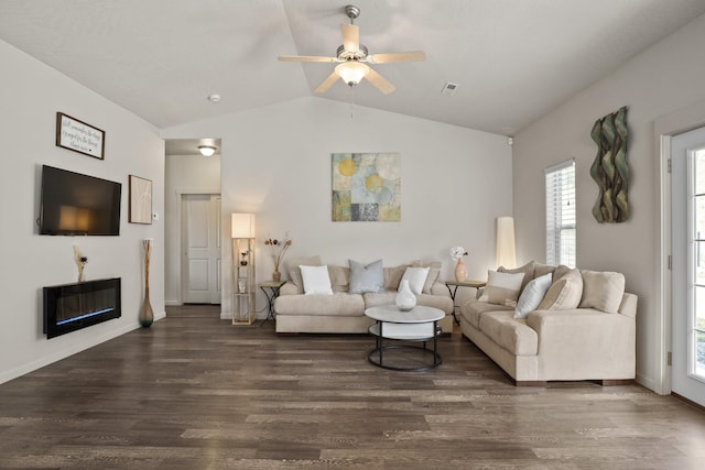 living room with dark wood-style floors, visible vents, a ceiling fan, lofted ceiling, and a glass covered fireplace