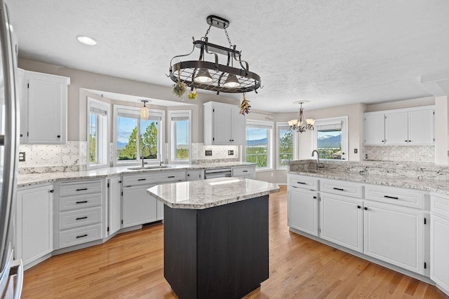 kitchen featuring a sink, white cabinets, light wood-style floors, and a chandelier