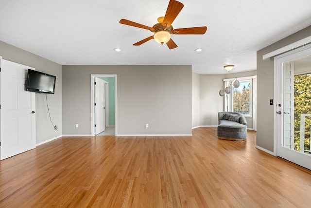 unfurnished living room featuring baseboards, light wood-type flooring, and ceiling fan