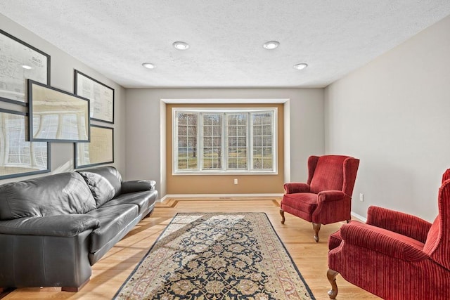 living room with recessed lighting, baseboards, light wood-style floors, and a textured ceiling