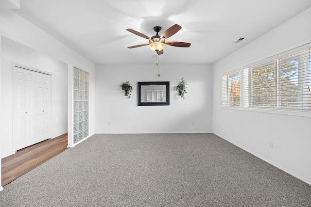 carpeted spare room featuring visible vents, baseboards, and a ceiling fan