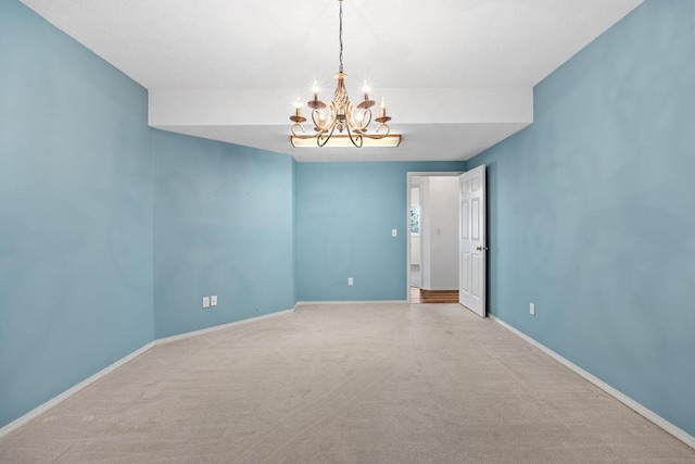 spare room with carpet flooring, a notable chandelier, and baseboards