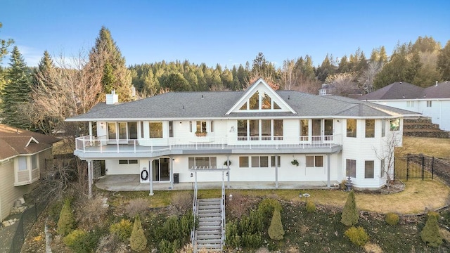 back of property featuring fence, stairs, a chimney, a balcony, and a patio