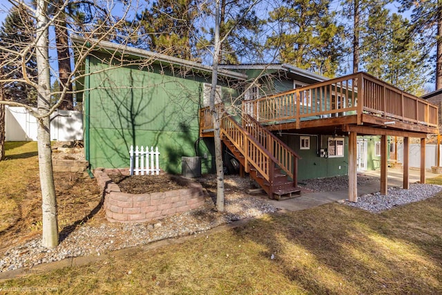 back of property featuring a lawn, stairs, a deck, and fence