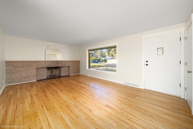 unfurnished living room with visible vents, baseboards, a fireplace, and light wood finished floors