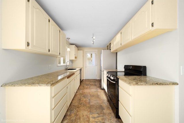 kitchen with light stone countertops, freestanding refrigerator, a sink, black electric range, and stone finish flooring