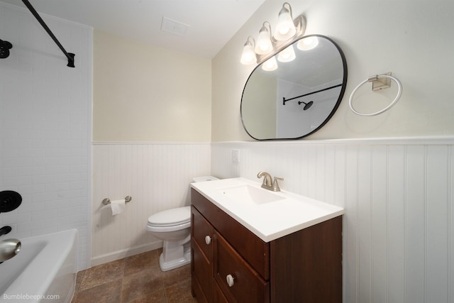 bathroom with a wainscoted wall, toilet, vanity, and shower / bathing tub combination