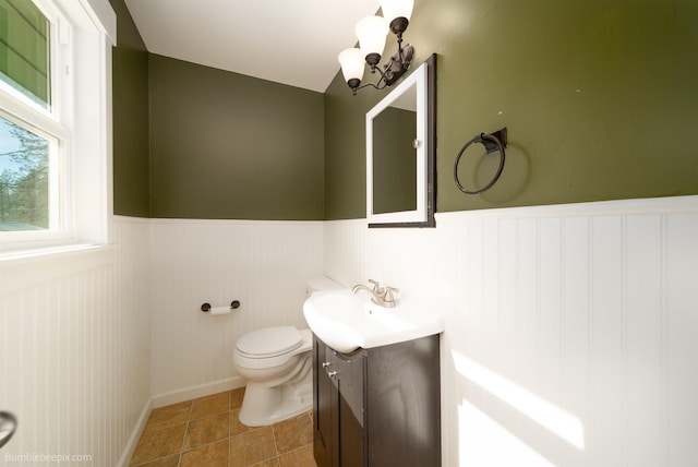 half bath featuring tile patterned floors, a wainscoted wall, toilet, and vanity