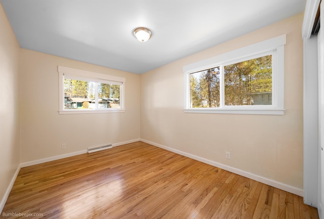 spare room with plenty of natural light, baseboards, light wood-type flooring, and a baseboard radiator