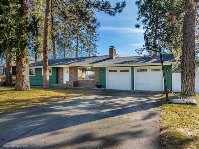 single story home featuring a front lawn, fence, concrete driveway, a garage, and a chimney