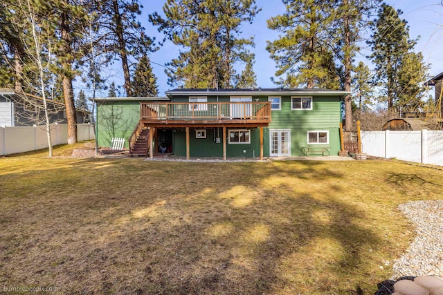 back of property with stairway, a wooden deck, a fenced backyard, french doors, and a lawn