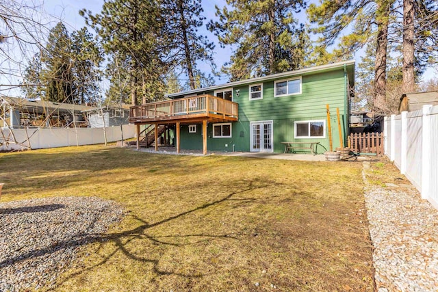 rear view of house featuring a deck, a fenced backyard, a yard, french doors, and stairs