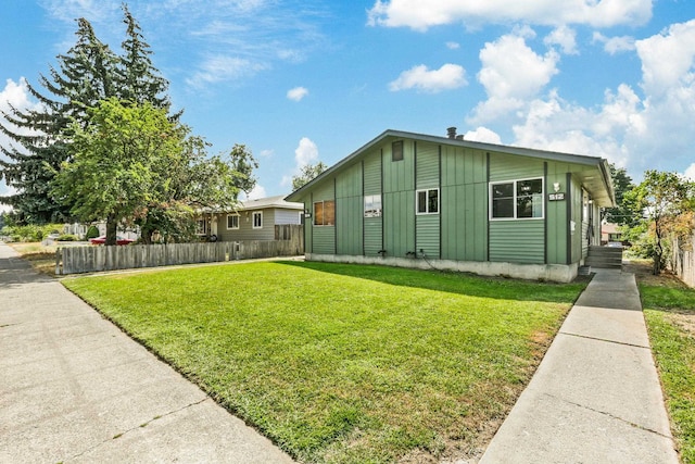 exterior space with board and batten siding, a yard, and fence