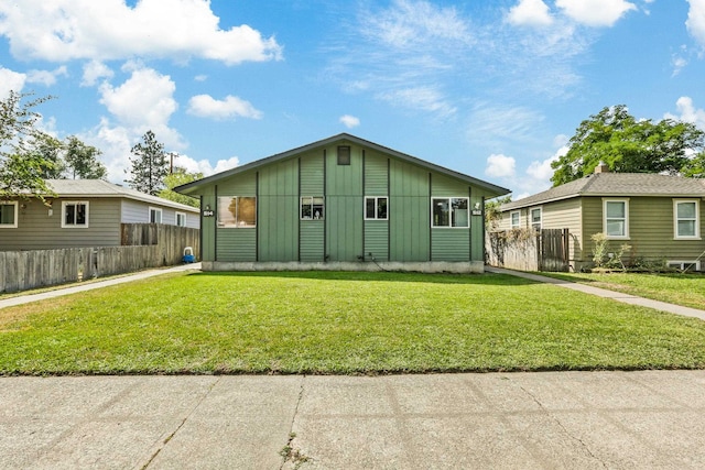 view of front of house with board and batten siding, a front yard, and fence