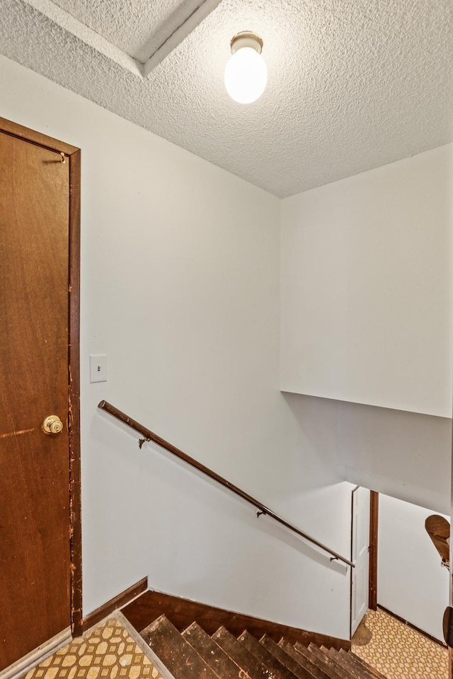 stairway with tile patterned floors, baseboards, and a textured ceiling