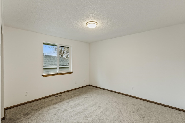 unfurnished room featuring visible vents, a textured ceiling, baseboards, and carpet floors