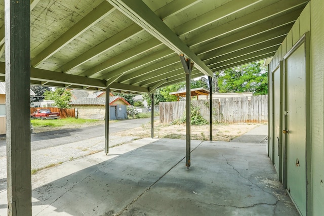 view of patio featuring a carport, an outdoor structure, and fence