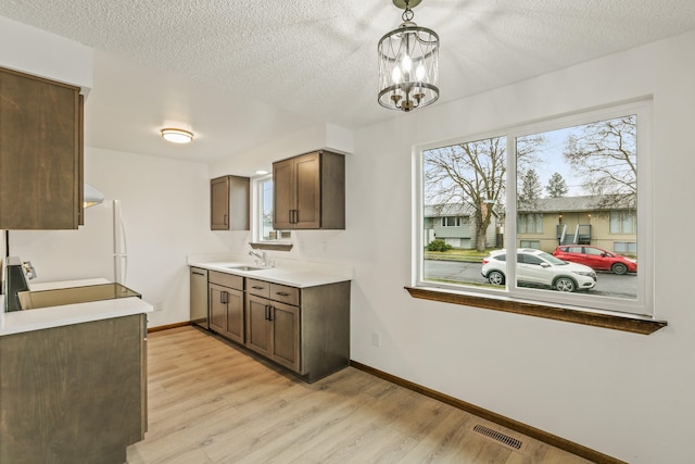 kitchen featuring visible vents, a sink, stainless steel dishwasher, light wood finished floors, and baseboards