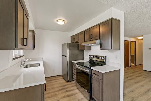 kitchen featuring a sink, under cabinet range hood, stainless steel appliances, light wood-style floors, and light countertops