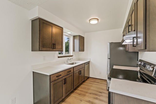 kitchen featuring a sink, stainless steel appliances, light wood-type flooring, and light countertops