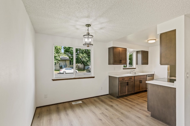 kitchen with visible vents, decorative light fixtures, light countertops, light wood-style flooring, and a sink