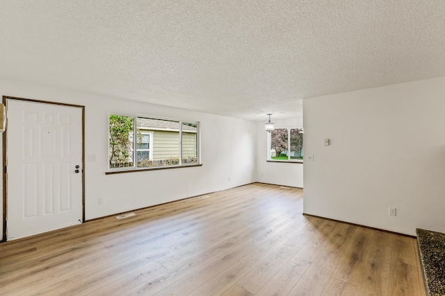 interior space featuring visible vents, a textured ceiling, and light wood-style flooring