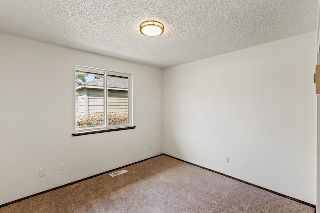 empty room with carpet flooring, baseboards, visible vents, and a textured ceiling