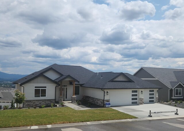8712 E Ridgeline Ln, Spokane, WA 99217 - view of front of house with stone siding, an attached garage, concrete driveway, and a front lawn