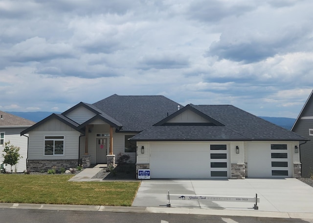 8712 E Ridgeline Ln, Spokane, WA 99217 - view of front of house with board and batten siding, stone siding, an attached garage, driveway, and a front lawn