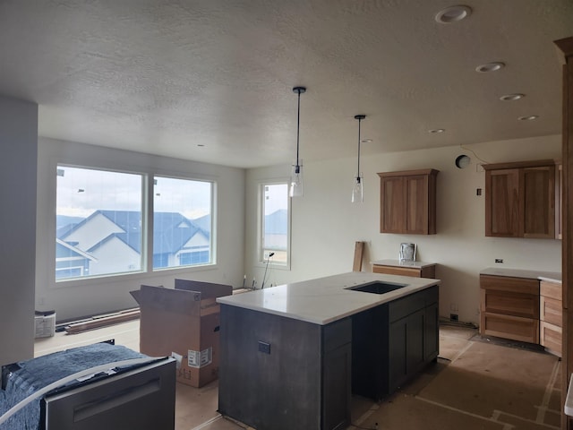 kitchen with a kitchen island, decorative light fixtures, recessed lighting, brown cabinetry, and a textured ceiling