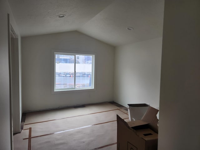 interior space featuring a textured ceiling and vaulted ceiling