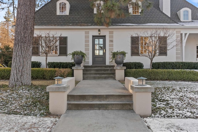 entrance to property featuring stucco siding and a high end roof