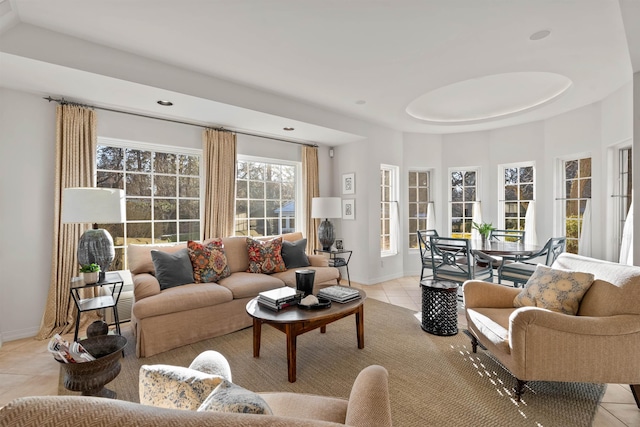 living area featuring a tray ceiling, light tile patterned floors, and baseboards