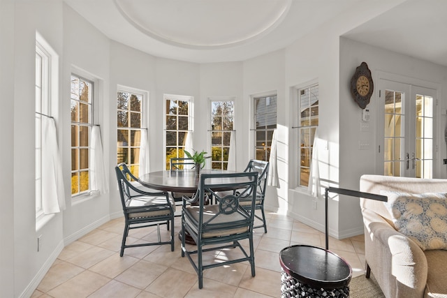 dining area featuring a raised ceiling, light tile patterned floors, french doors, and baseboards