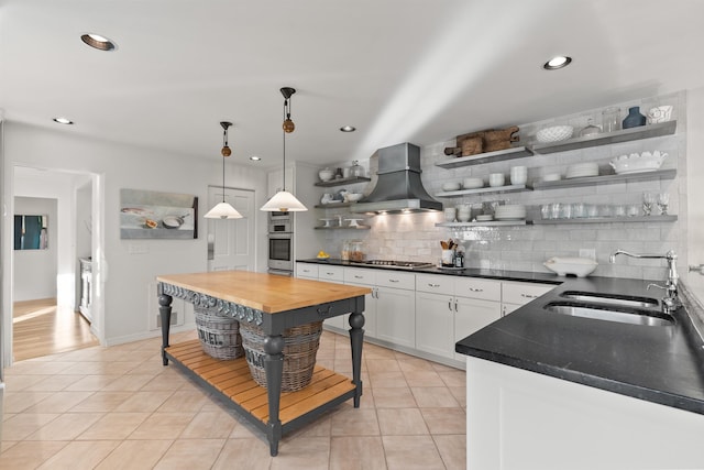 kitchen featuring backsplash, open shelves, custom range hood, light tile patterned floors, and a sink