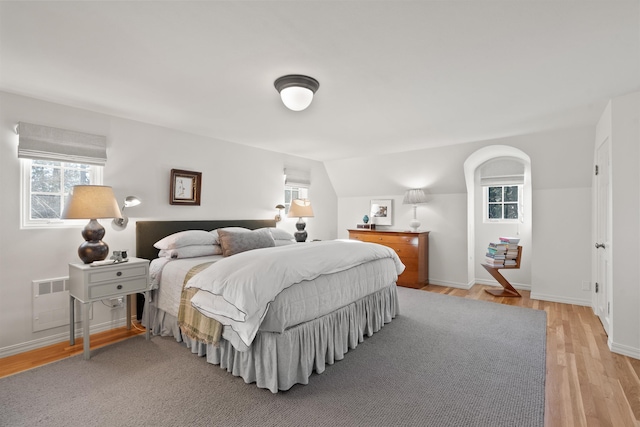 bedroom with lofted ceiling, light wood-style flooring, multiple windows, and baseboards